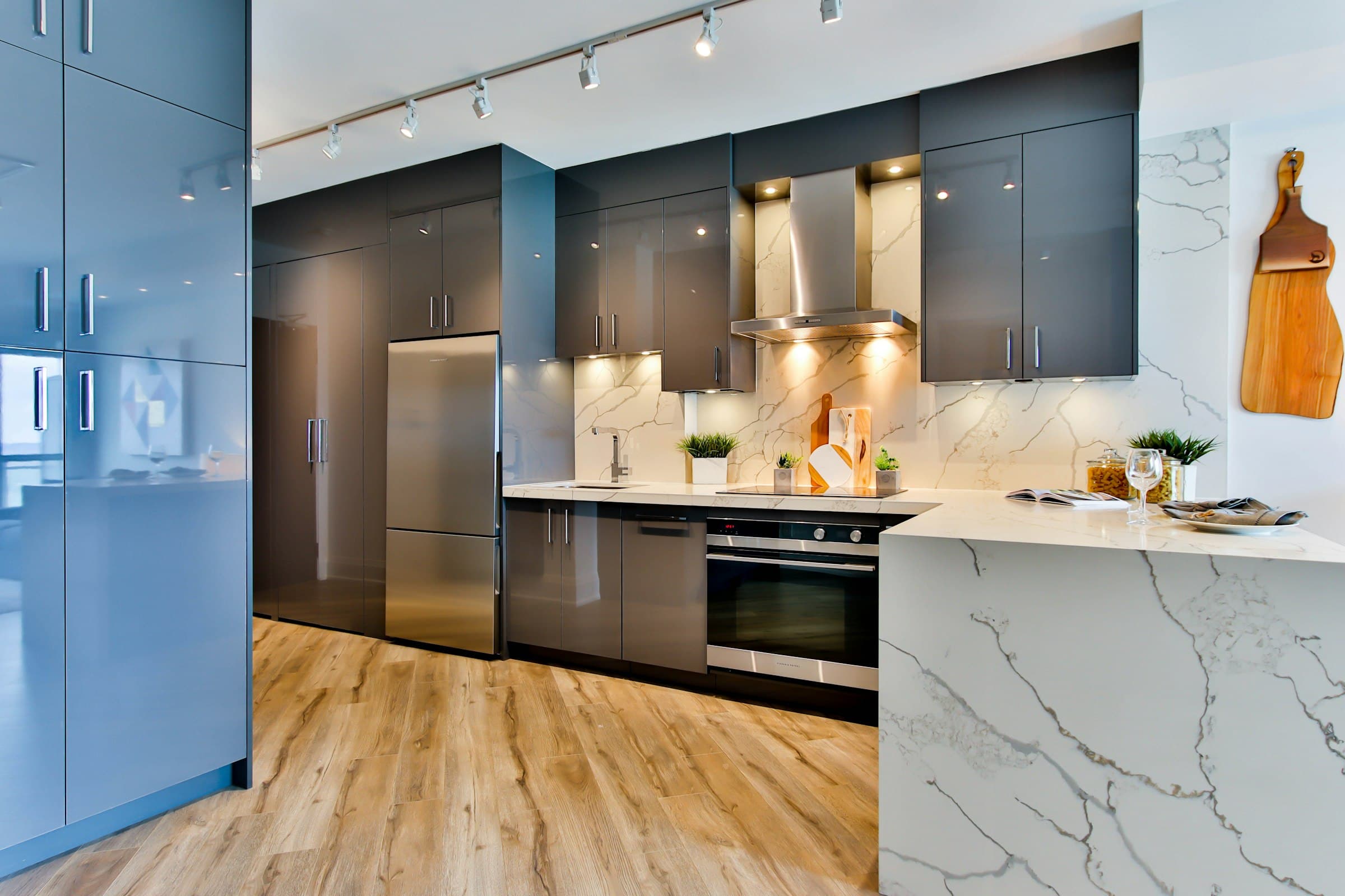 Modern kitchen with dark cabinetry, a marble backsplash and warm pendant lighting